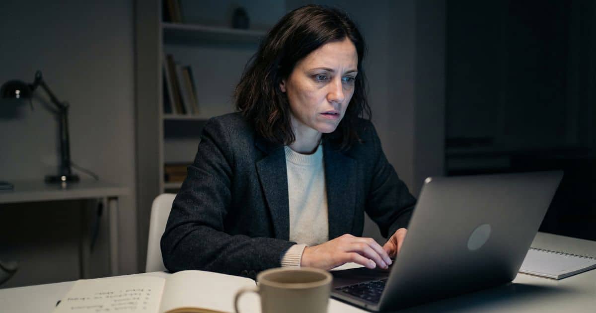 Generic AI output frustration, female creator at laptop in dim home office at night reviewing vague content