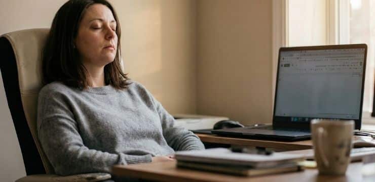 productivity quotes for focus, female creator closing eyes at desk during afternoon cognitive reset