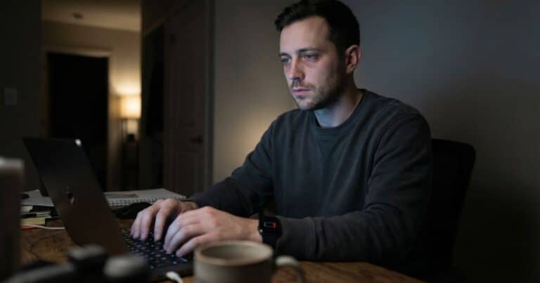 Resilience and rest concept, exhausted man working late at laptop in dark home office at night