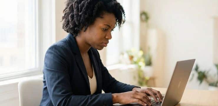 Social media keyword strategy for discovery, a female creator rewriting content on laptop at desk near window