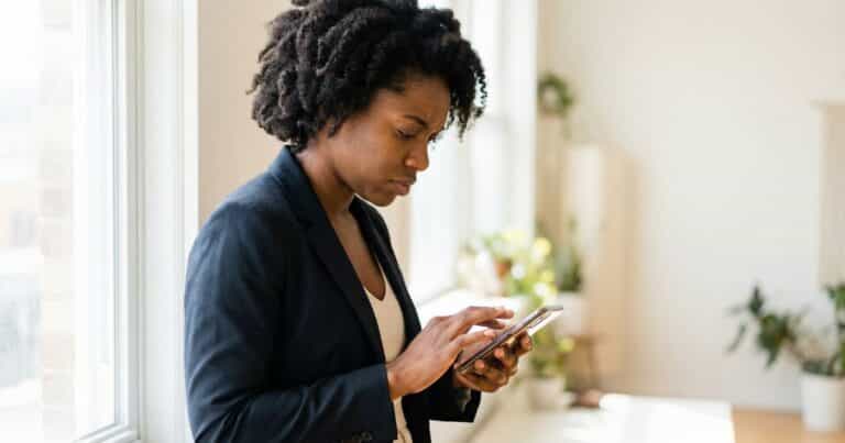 Social media caption optimization for search, female creator using phone one-handed near window in daylight